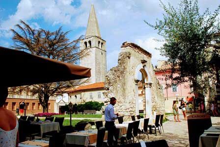Restos romanos en la plaza Marafor y el campanario de la Basílica Eufrásica en Porec (Croacia)